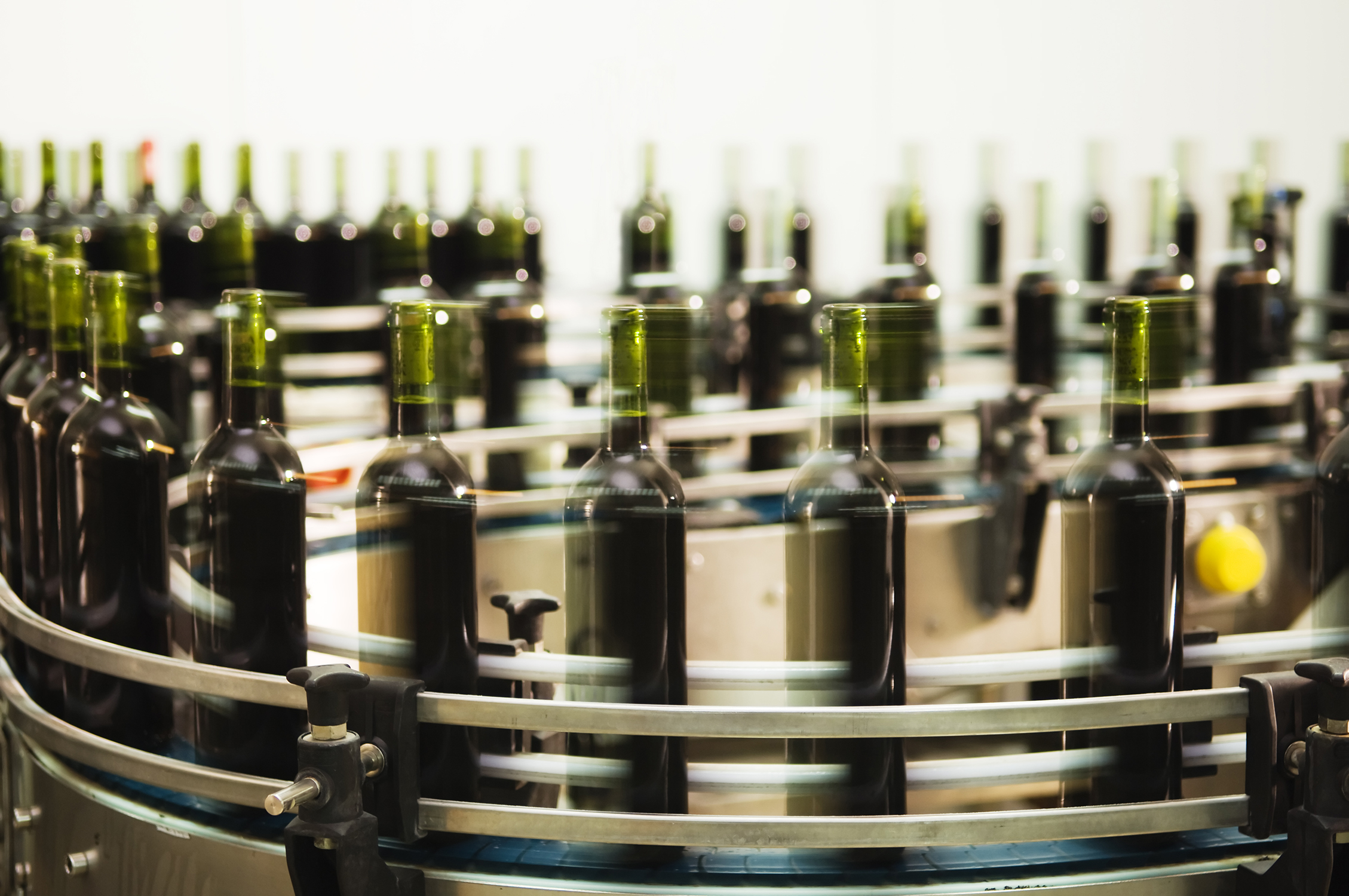 A German wine producer uses a series of conveyors to transport their bottles through the production process. At the end of the system, the bottles are buffered and accumulated on a spiral conveyor. (Image Source: istock-97151143 – mrfotos)